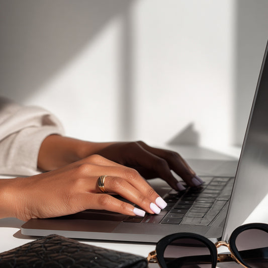 RBF Studio team member typing on a laptop with a neutral background preparing content for a new Shopify store.